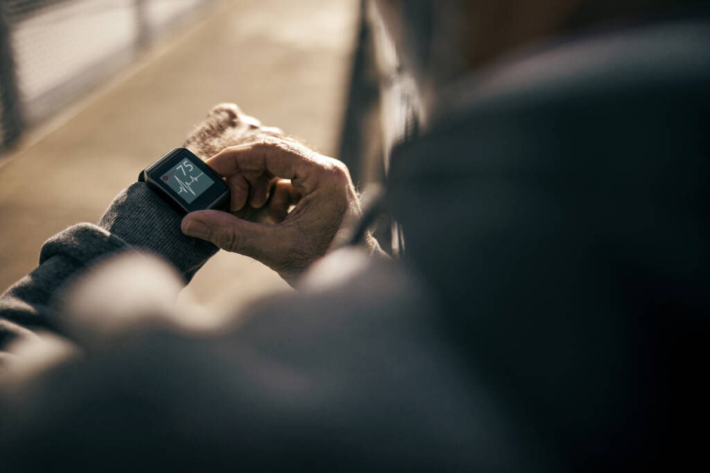 Senior Man on a bridge using Smart Watch measuring heart rate